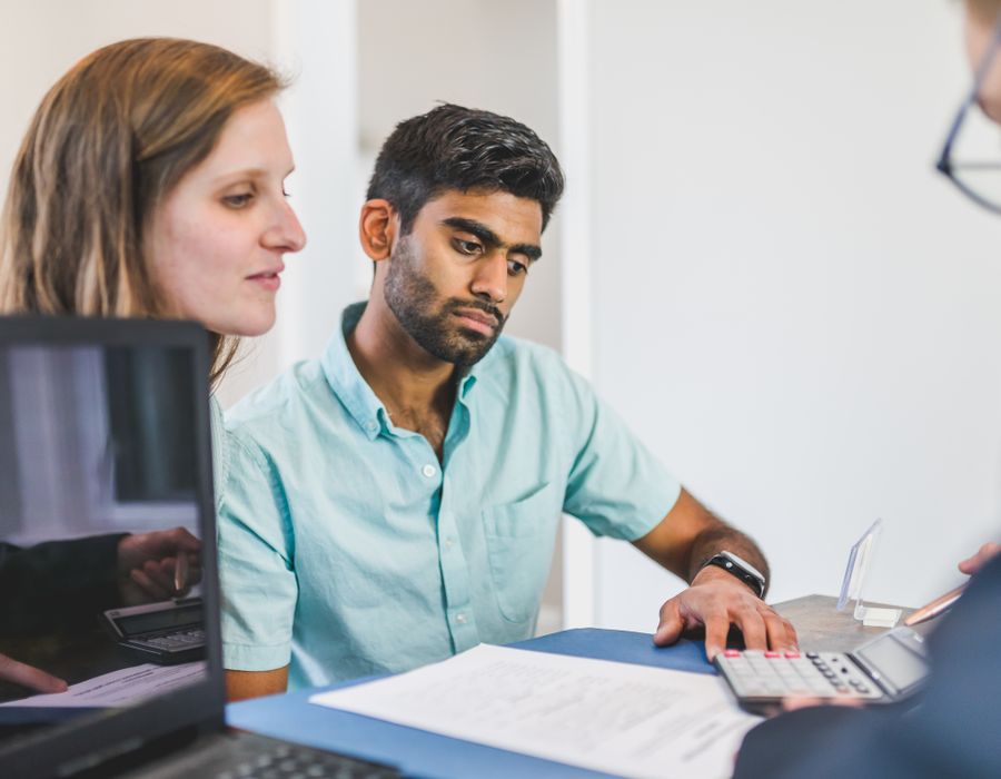 A young couple discussing their home loan options with a mortgage broker at a desk